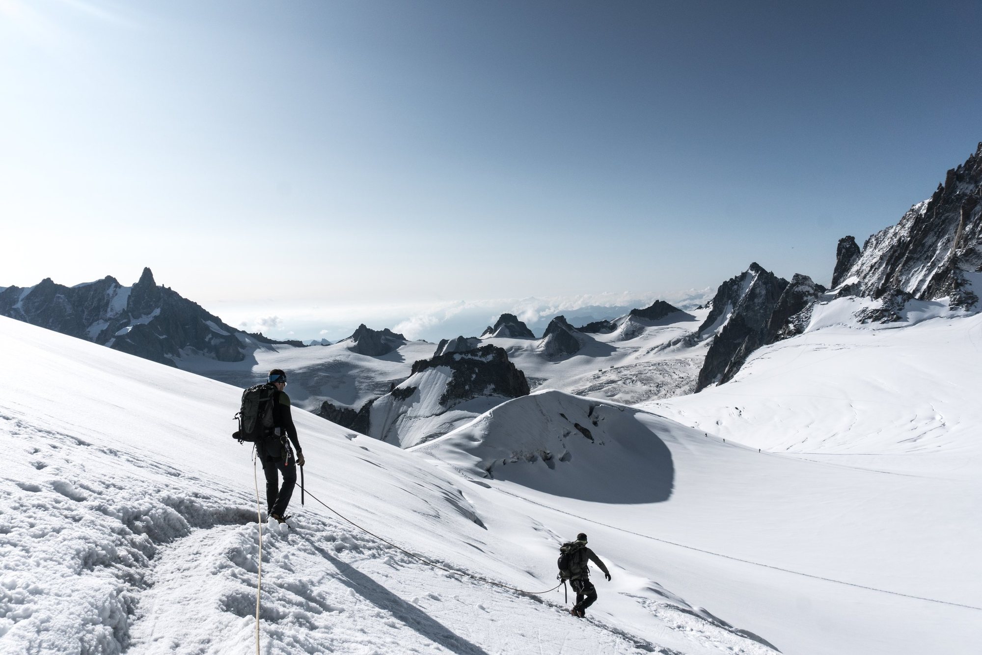 Zwei Bergführer am Seil auf einem sonnigen Gletscher, der Vordere führt