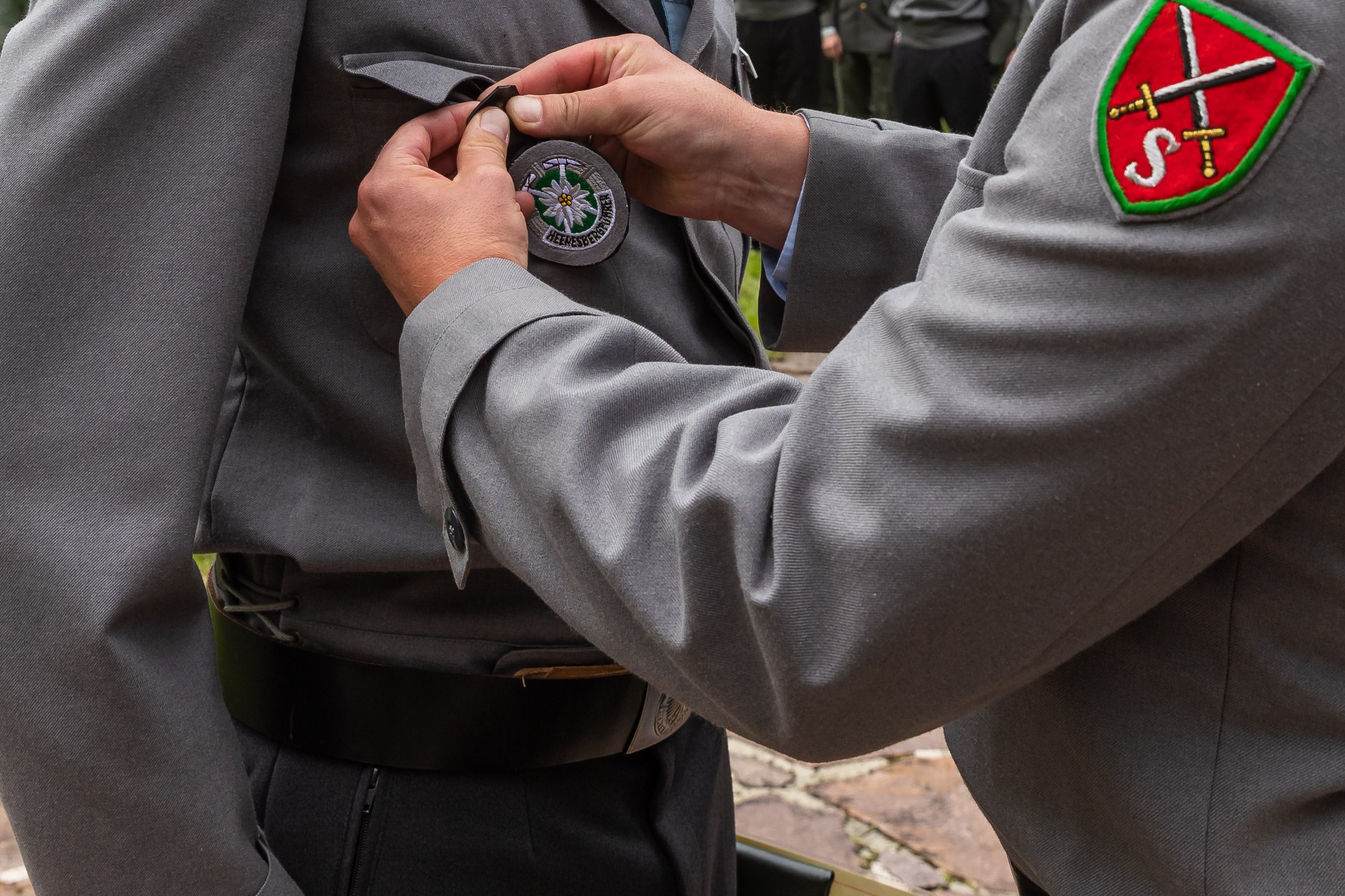 Bei der Ernennung wird das Heeresbergführerabzeichen an die graue Uniformjacke gesteckt