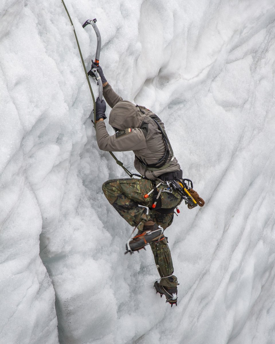 Soldat mit Eisgeräten und Steigeisen in einer Gletscherwand