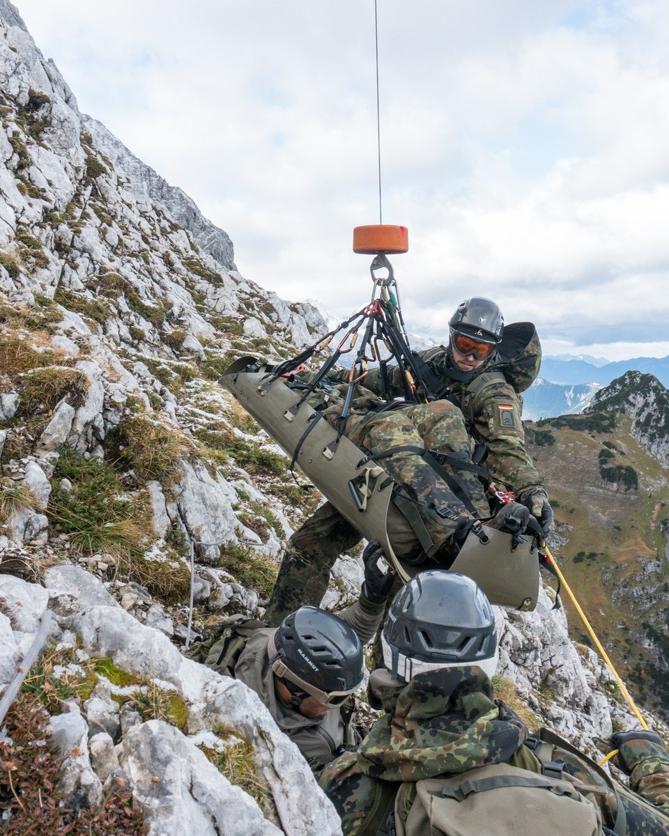 Soldaten sichern eine Trage am Windenhaken an der Felswand