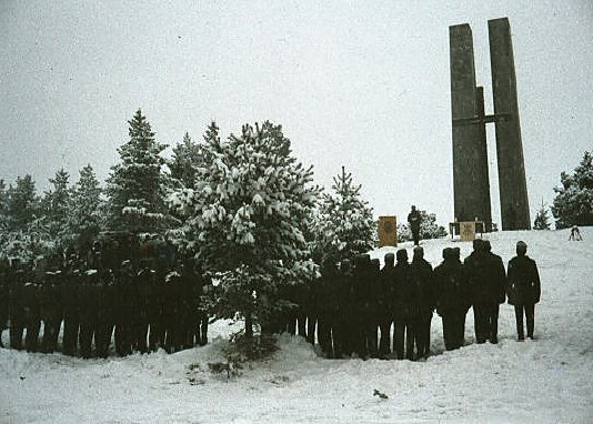 Historische Farbaufnahme: Soldaten stehen im Schnee vor dem Gebirgsjägerehrenmal, von hinten gesehen