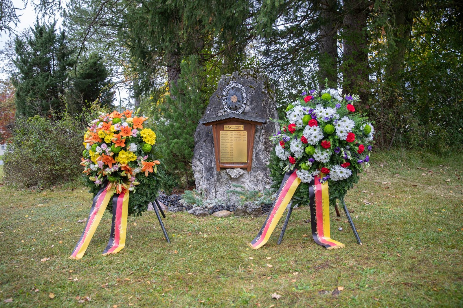 Zwei Kränze mit Schleifen in Schwarz-Rot-Gold vor dem Gedenkstein der Heeresbergführer
