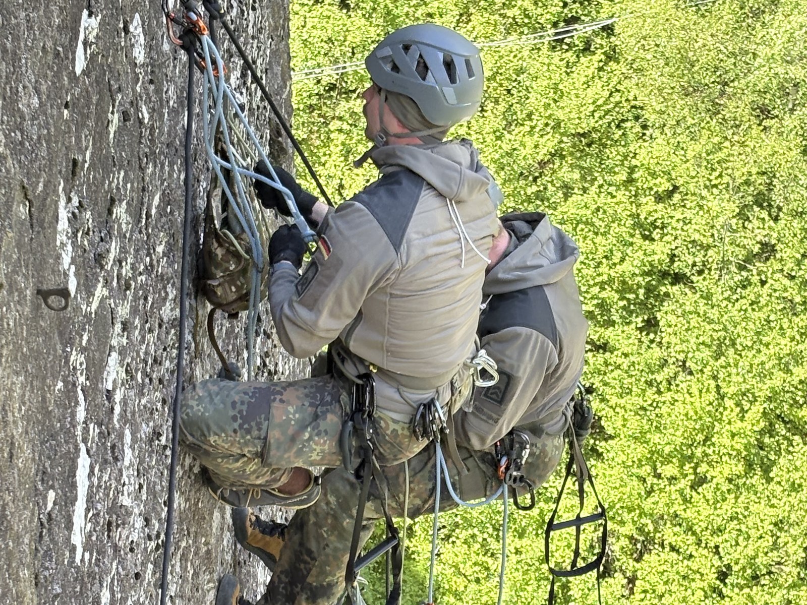 Zwei Soldaten steigen mit Trittleitern und Materialsack eine senkrechte Felswand hinauf