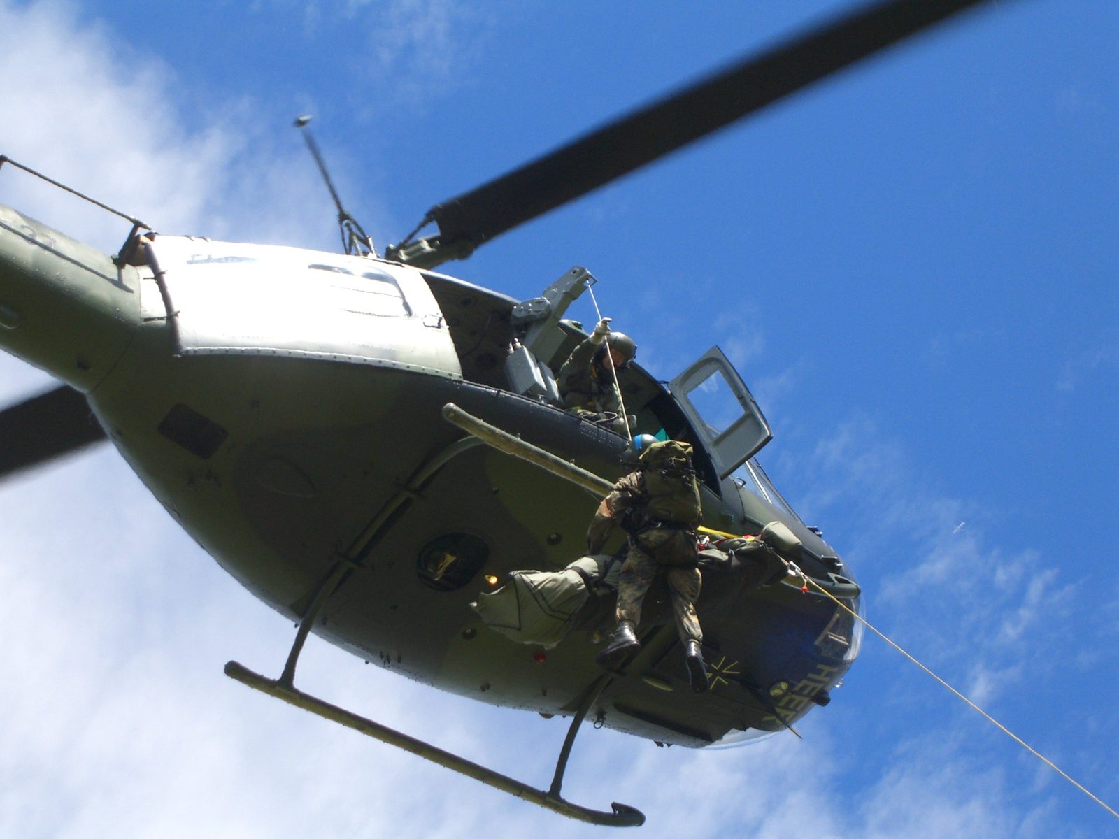 Ein Soldat hängt an der Rettungswinde einer UH-1D in der Luft