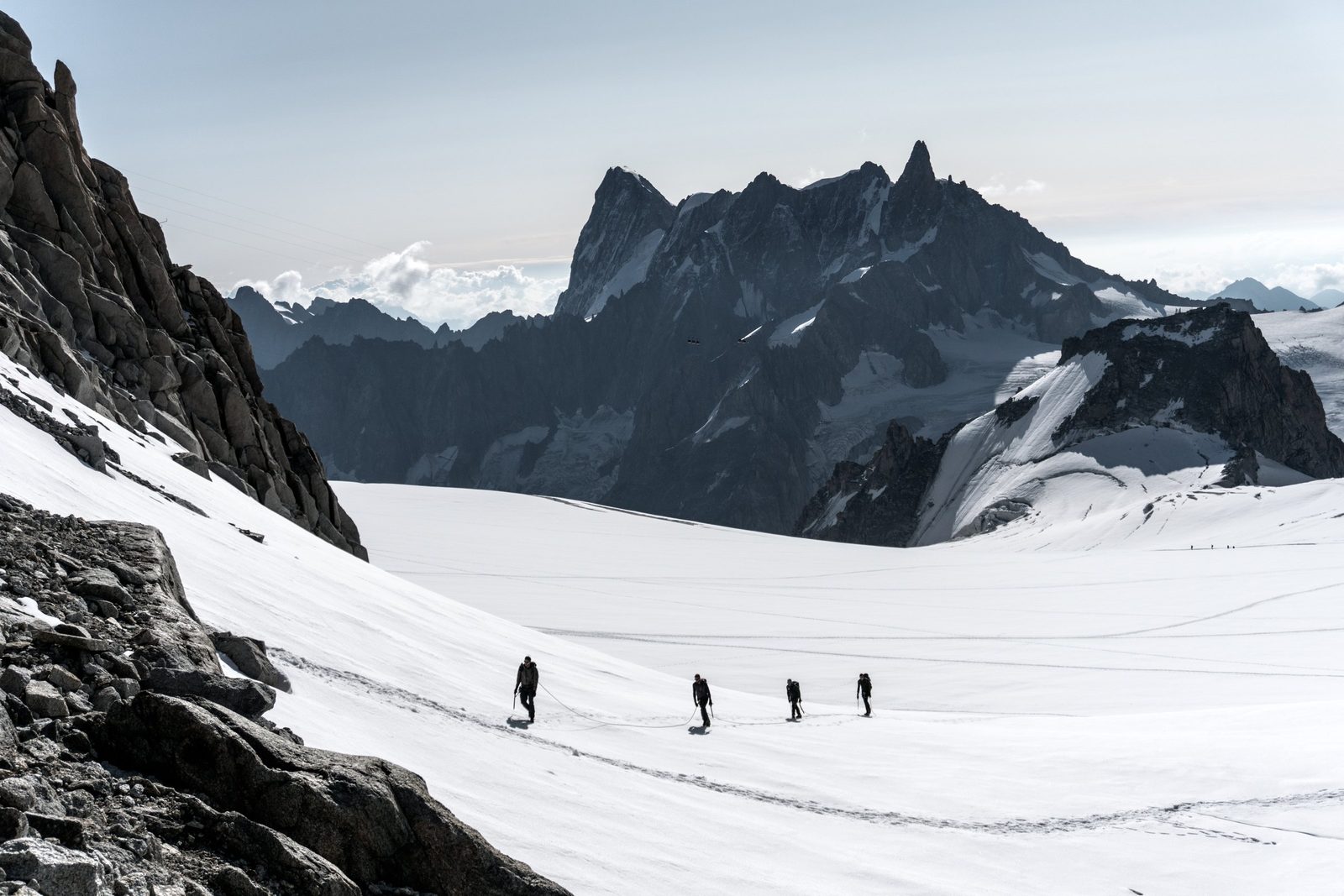 Eine Seilschaft geht in einer Reihe über einen Gletscher vor schroffen Felsgipfeln
