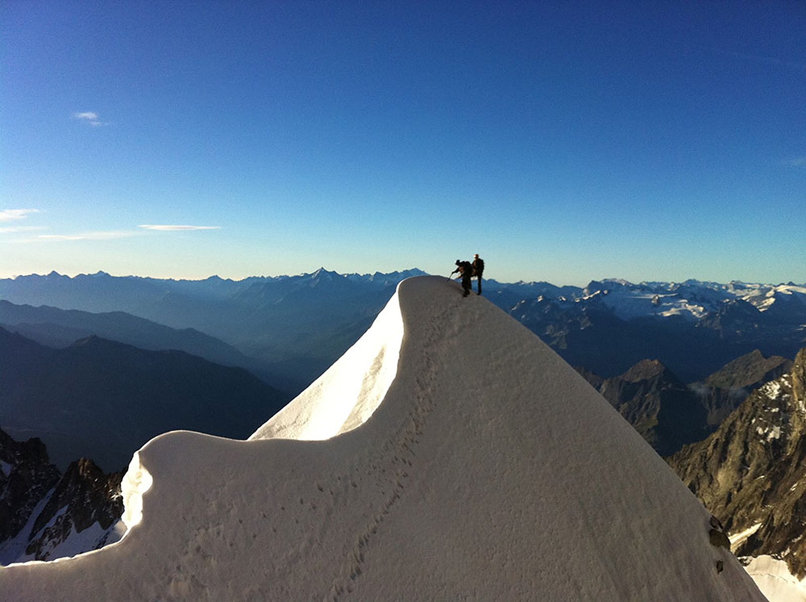 Seilschaft auf einem verschneiten Grat vor blauem Himmel