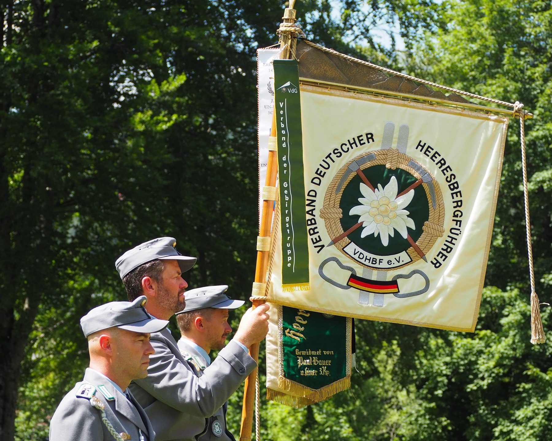 Fahnenträger in Uniform mit der Verbandsfahne: Edelweiß und Schriftzug Verband Deutscher Heeresbergführer