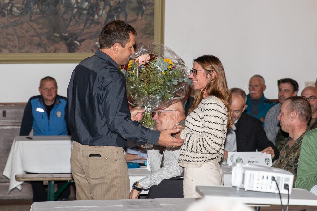 Festakt: Blumenstrauß wird im Saal an eine Frau überreicht