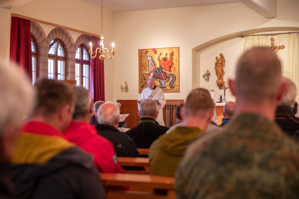 Gottesdienst: Besucher in den Bankreihen blicken auf den Geistlichen in Weiß