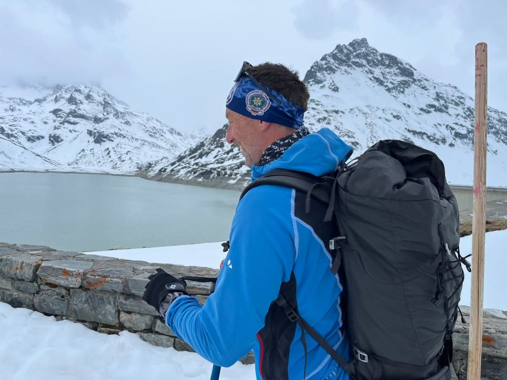 Frühjahrstreffen 2025: Skitourengeher mit Stirnband und Rucksack am Stausee vor Bergkulisse